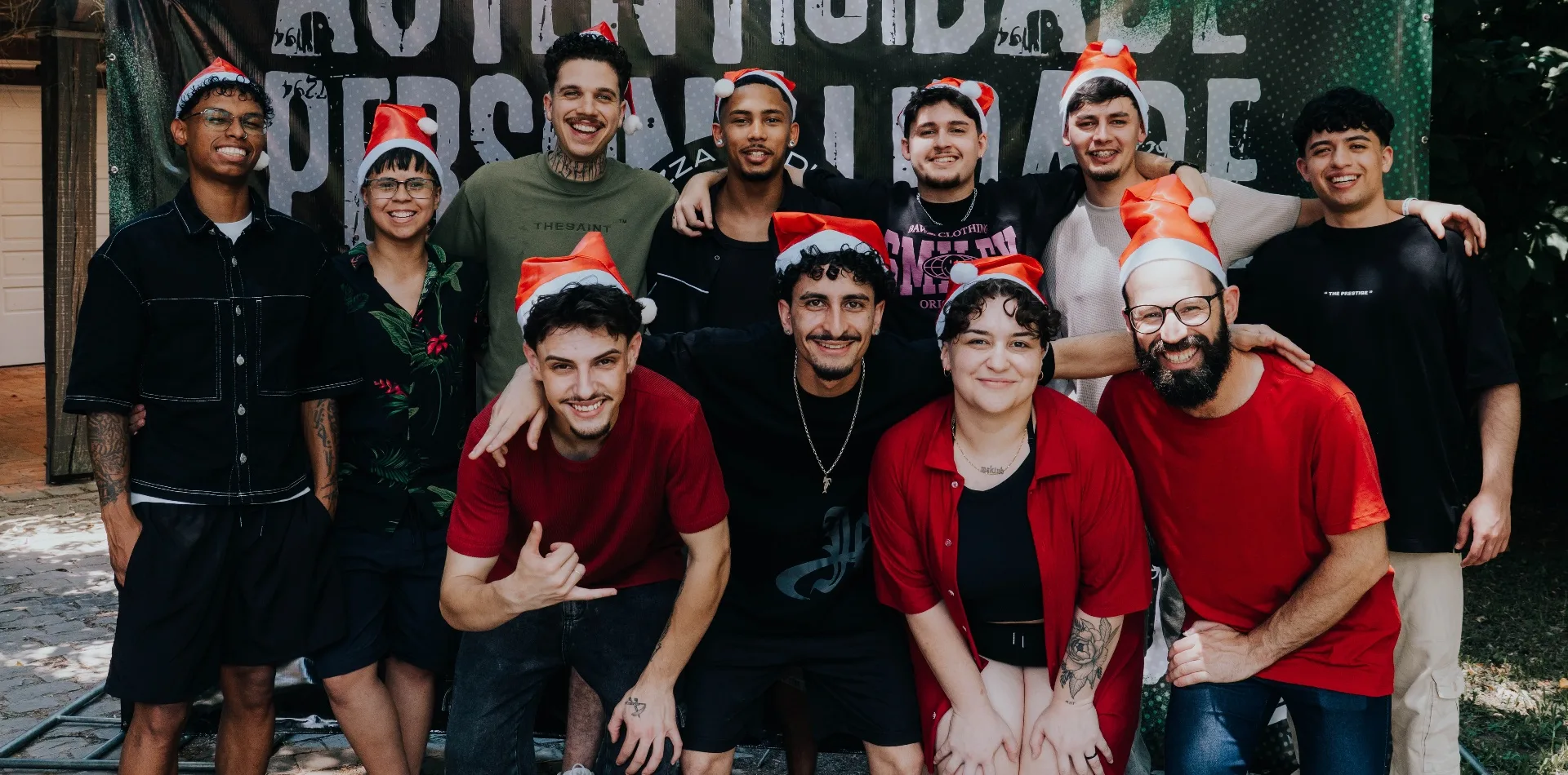 Equipe da Meduzza Barbearia: doze pessoas posando juntas, sorrindo, diante de uma faixa da barbearia.